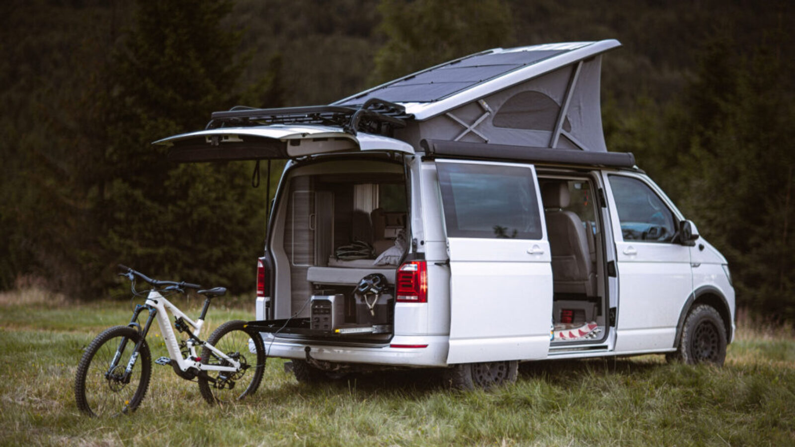 Kamper VW California z panelami fotowoltaicznymi na dachu, rowerem elektrycznym i stacją EcoFlow DELTA 3 Plus podczas testu w górach.